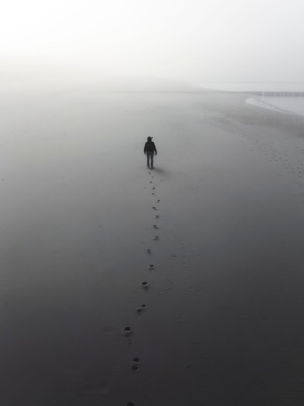Sylwetka człowieka na zamglonej plaży